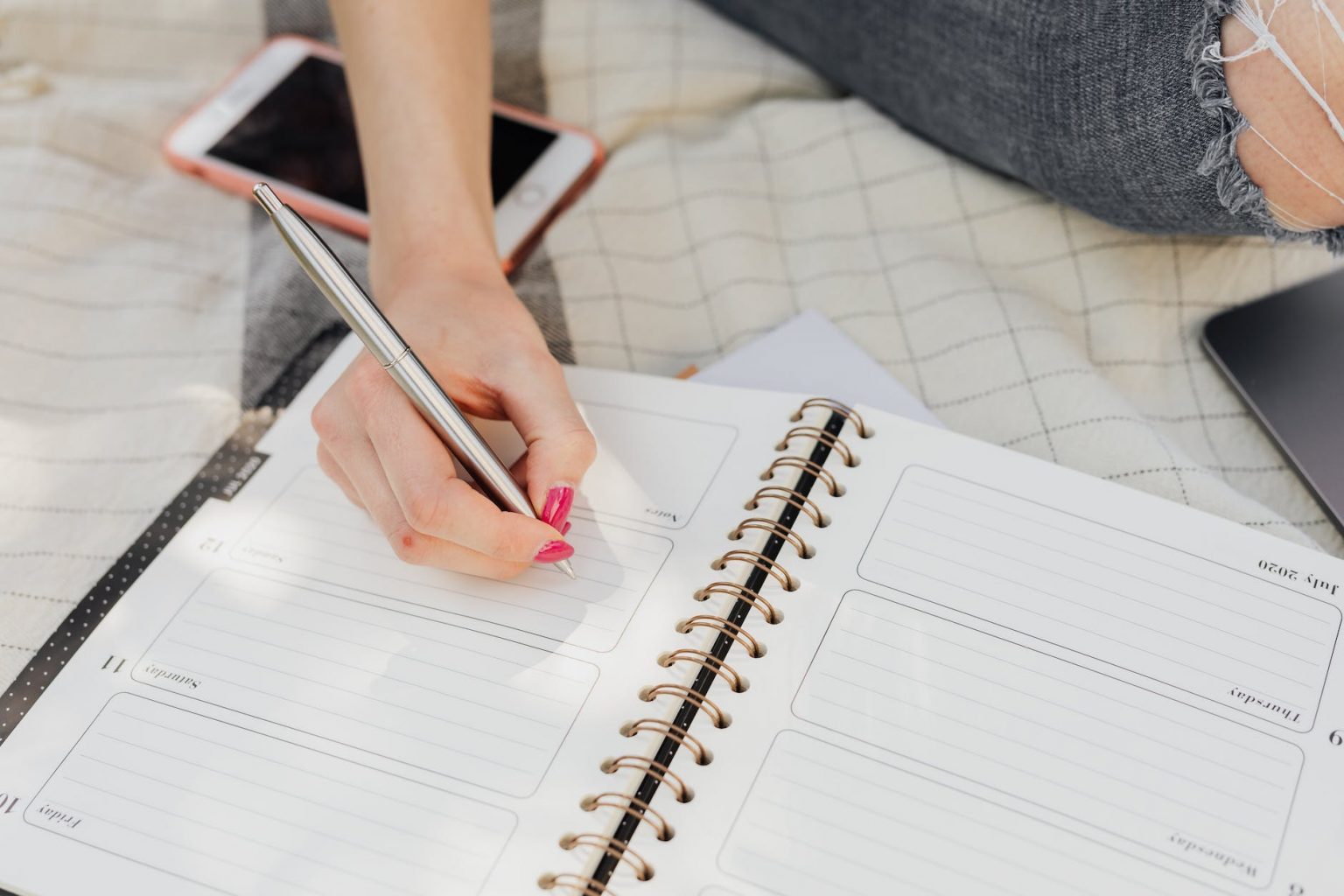 crop woman taking notes in diary while sitting in park